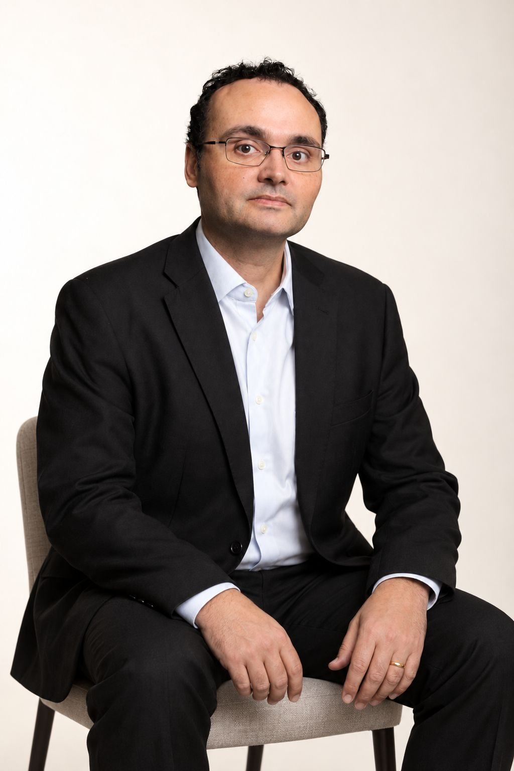 Retrato do Dr. Fernando Lemgruber, sentado, de blazer escuro e camisa clara, em fundo claro.